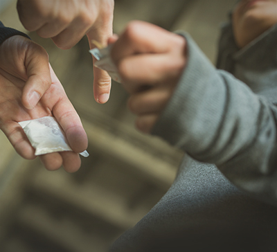 Человек покупает пакетик наркотиков